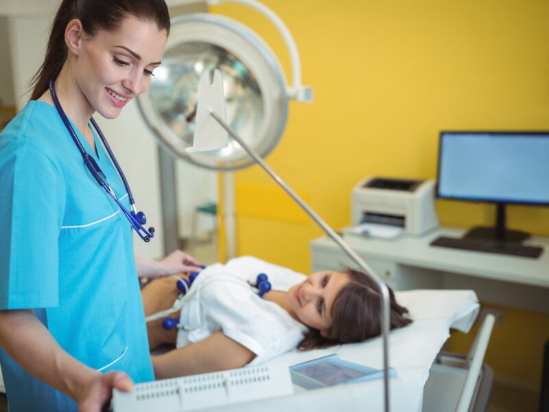 Nurse performing an electrocardiogram test on the patient