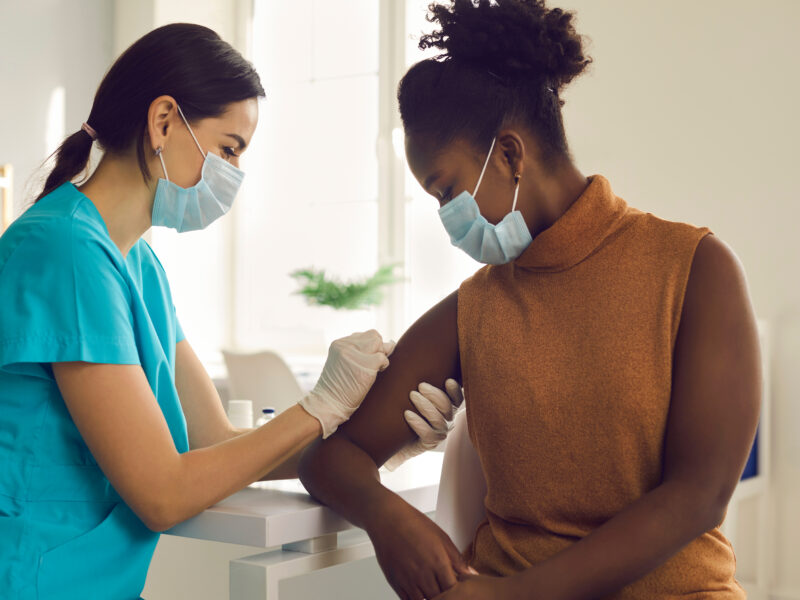 Young African-American woman getting seasonal influenza shot or modern Covid-19 vaccine